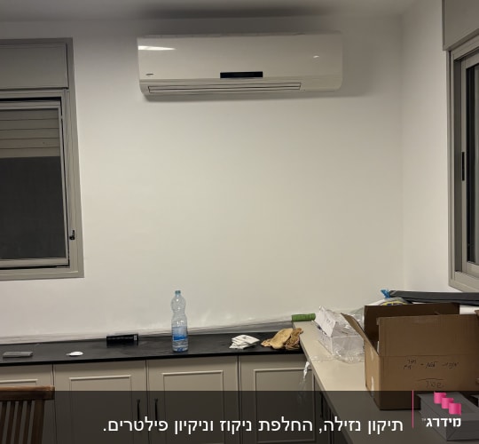חדר עם מזגן מותקן על הקיר וארונות מטבח